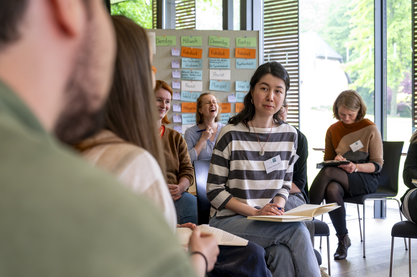 Foto einer Frau, die in einer Gruppe sitzt und aufmerksam zuhört.