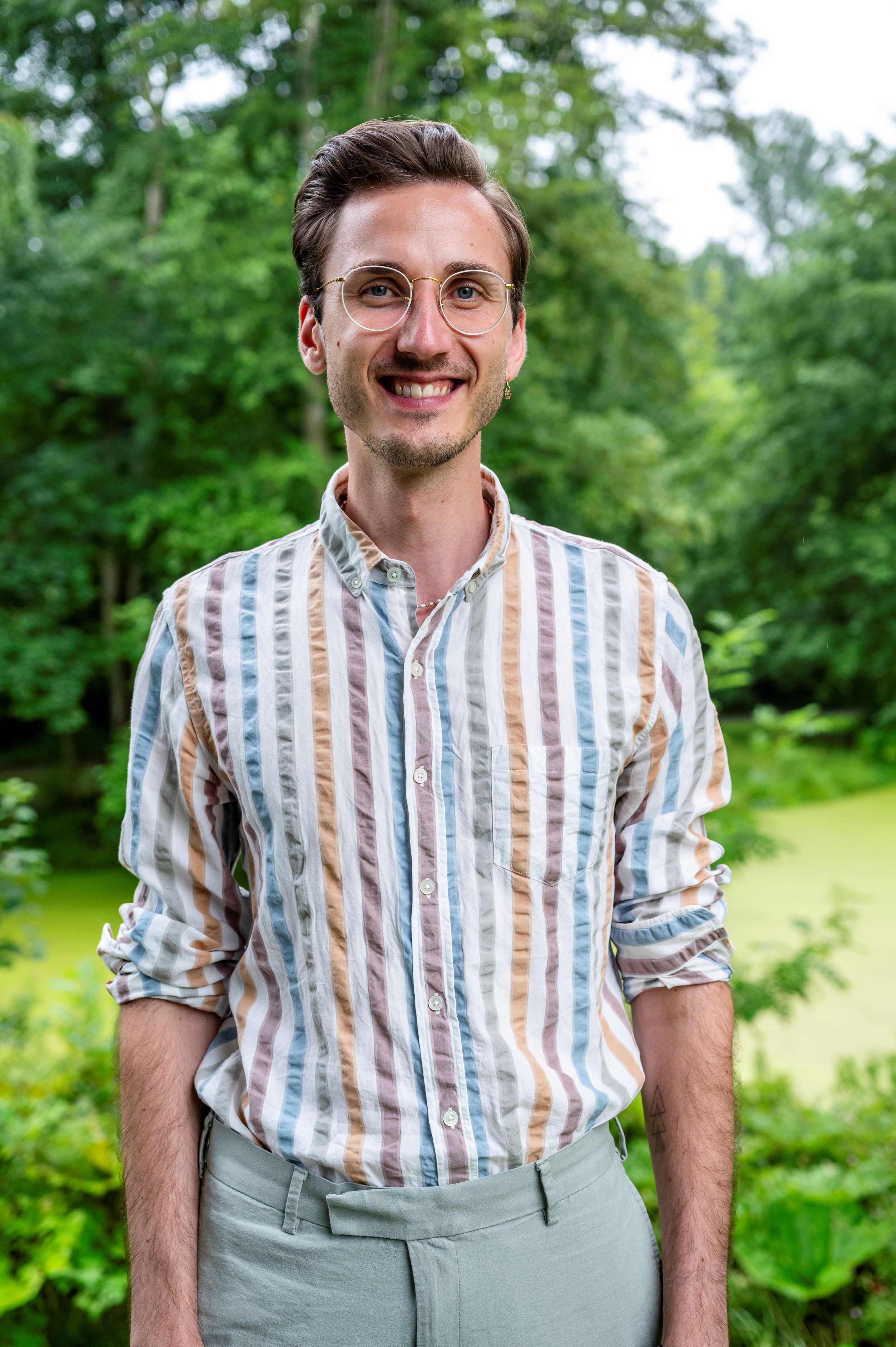 Foto eines Mannes mit Brille und längsgestreiften Hemd.